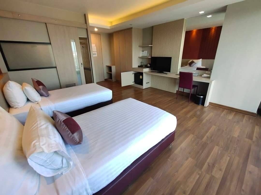 Ein Hotelzimmer mit zwei Betten, einem Fernseher, einem Schreibtisch und einem Sessel.