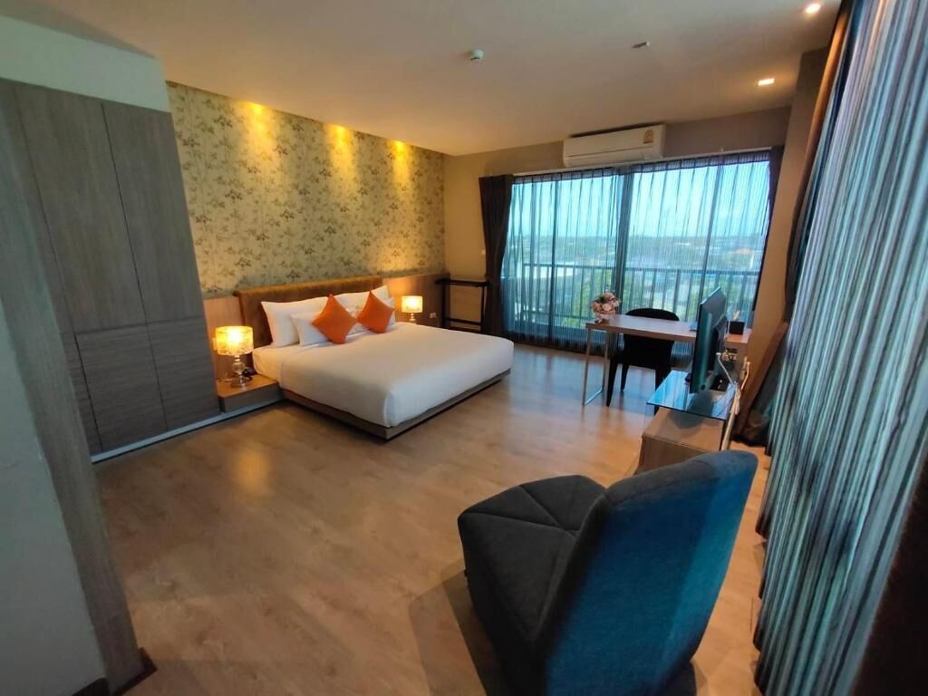 A hotel room with a bed, a desk, and a view of the city.