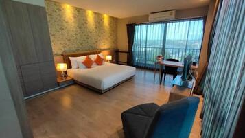 A hotel room with a bed, a desk, and a view of the city.
