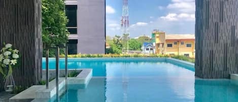 A swimming pool with a view of a tall communication tower, surrounded by buildings and greenery.