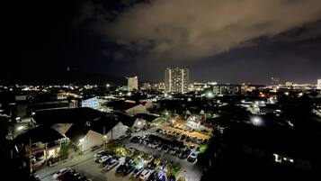 A nighttime view of a cityscape with a parking lot, buildings, and a prominent high-rise in the background.