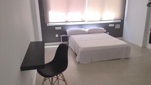 Un dormitori amb llit, escriptori i cadira.