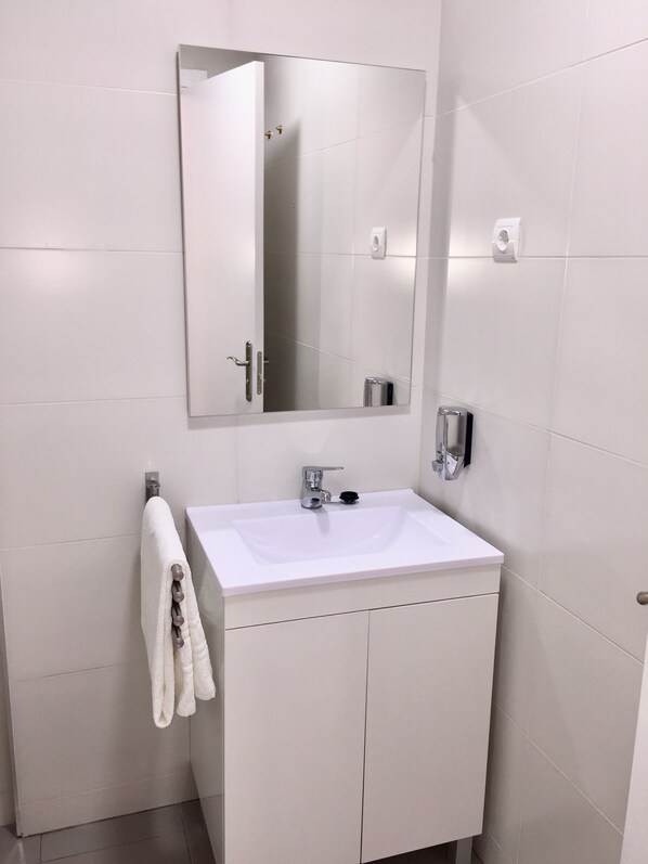 A modern bathroom with a white sink, a mirror, and a towel rack.