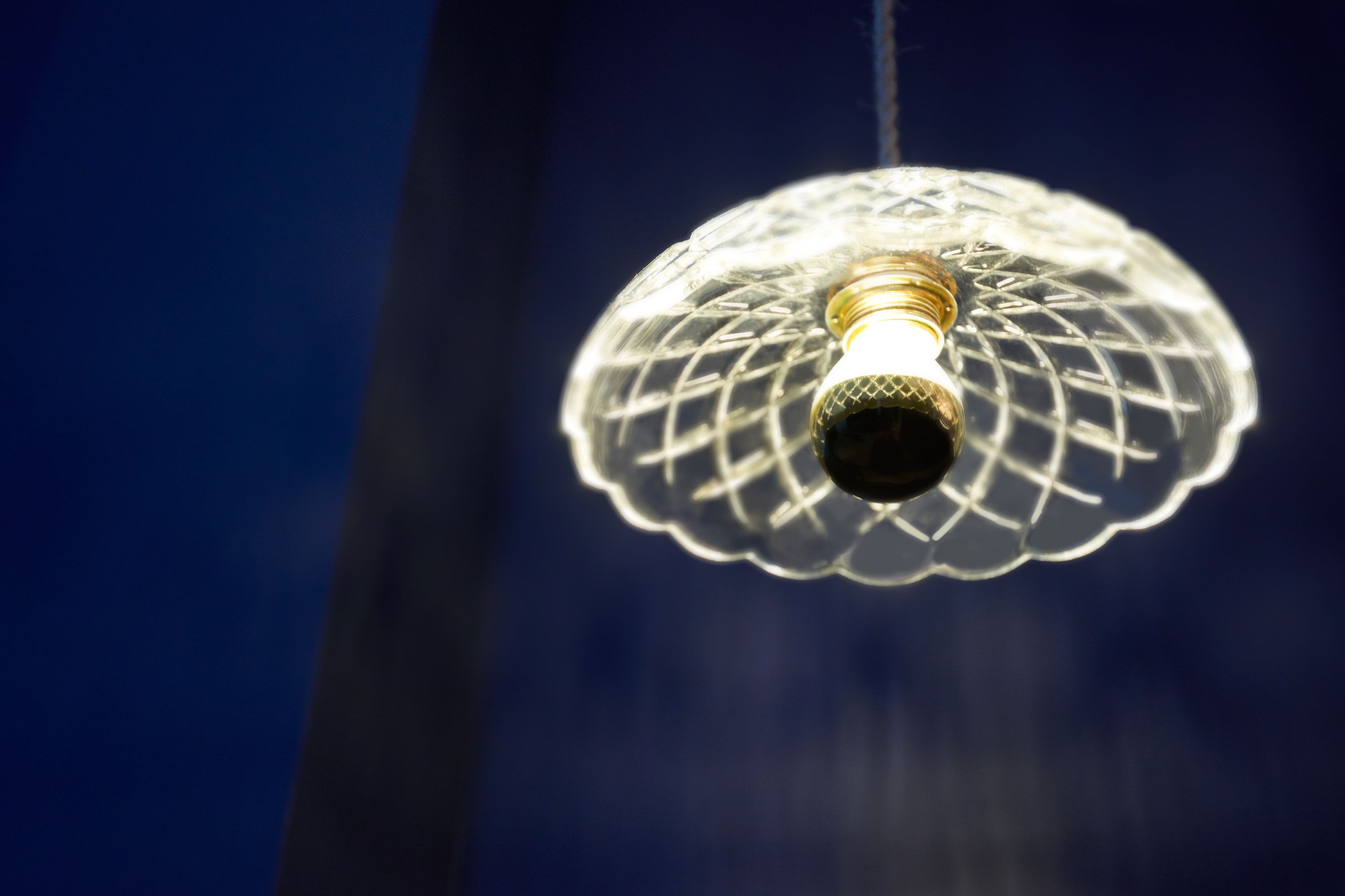 Een hanglamp met een heldere, gematte glazen kap en een zichtbare gloeilamp.