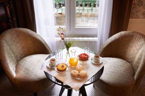 Una escena de desayuno con dos sillas, una mesa y vistas por la ventana.