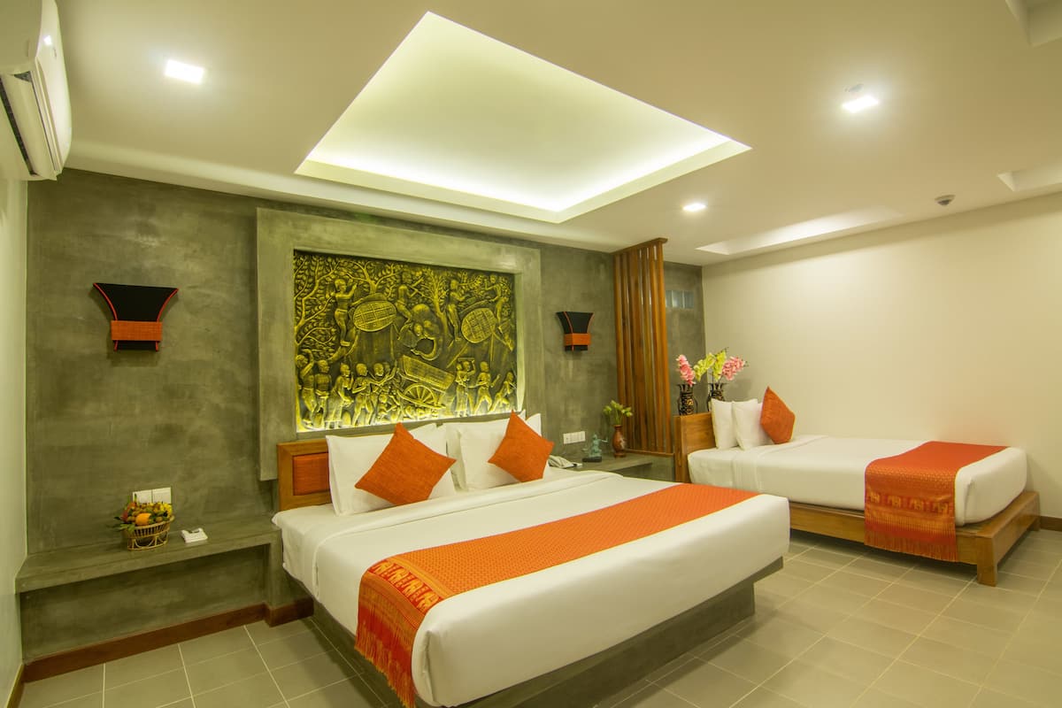 Une chambre d’hôtel avec deux lits, une grande œuvre d’art au mur et une lucarne.