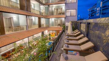 Una piscina al aire libre, sombrillas, sillones reclinables de piscina