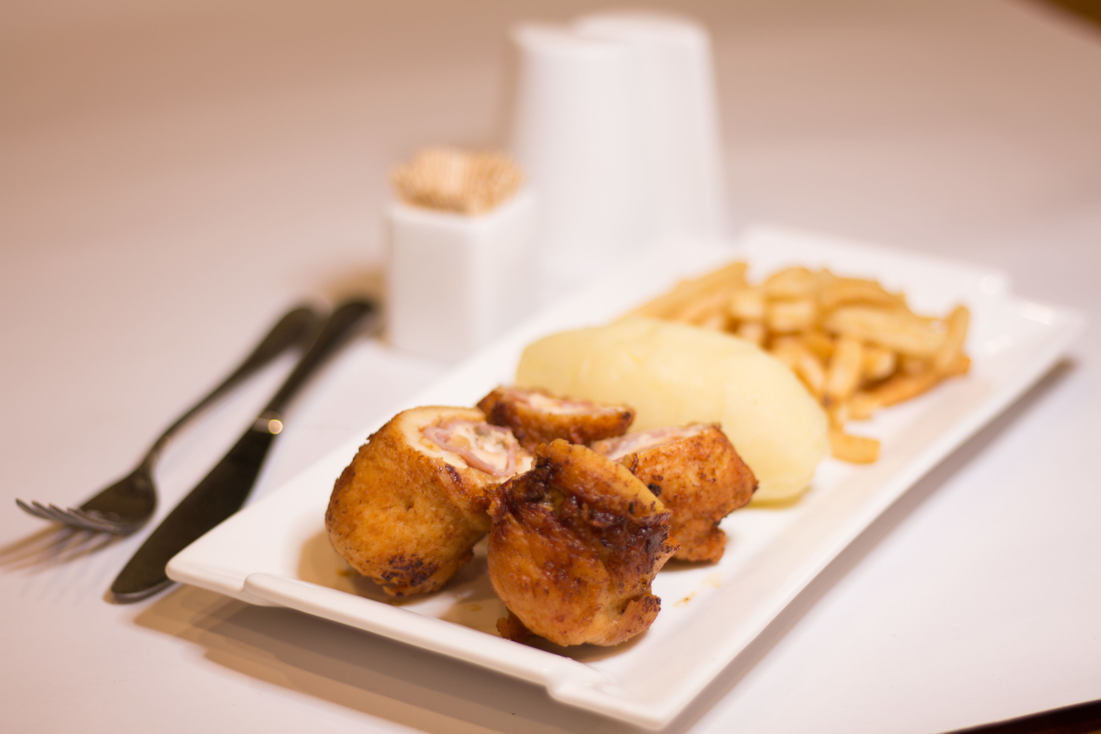 A plate with chicken, mashed potatoes, and fries.