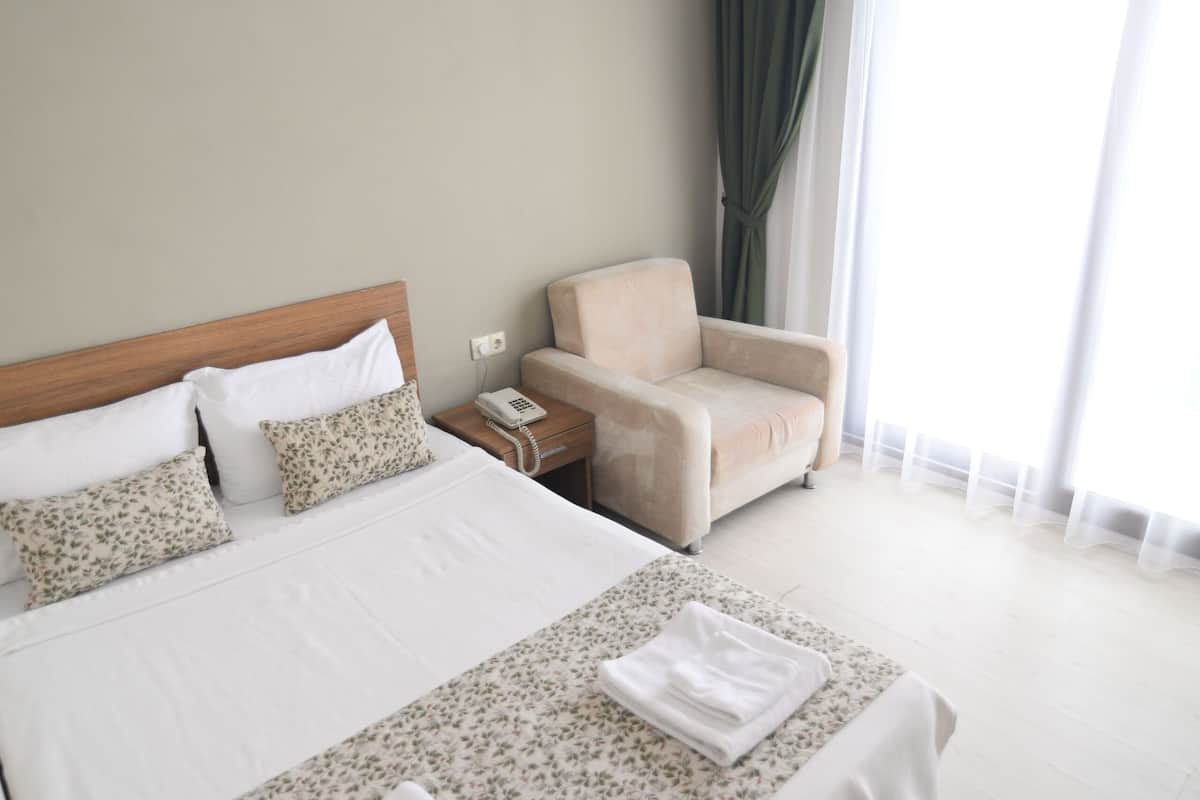 Une chambre d’hôtel équipée d’un lit, d’une chaise, d’une table de chevet et d’un appareil de climatisation.