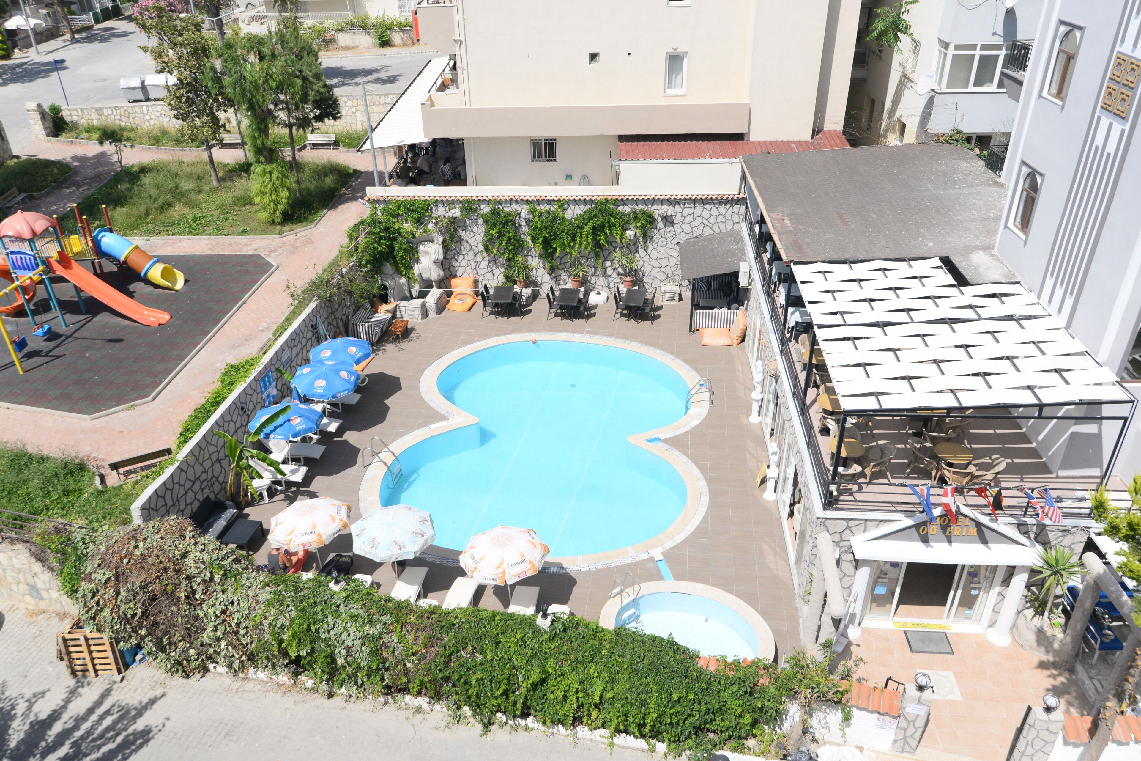 A swimming pool with lounge chairs and umbrellas, surrounded by a stone wall and greenery.