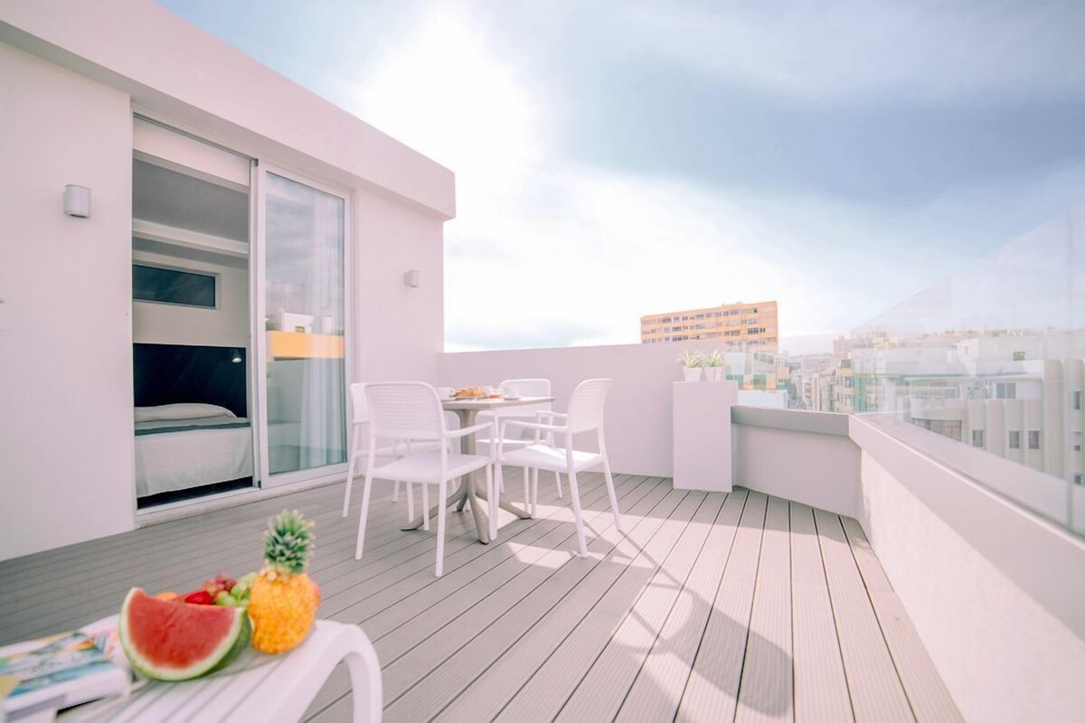 A balcony with a table, chairs, and a bed.