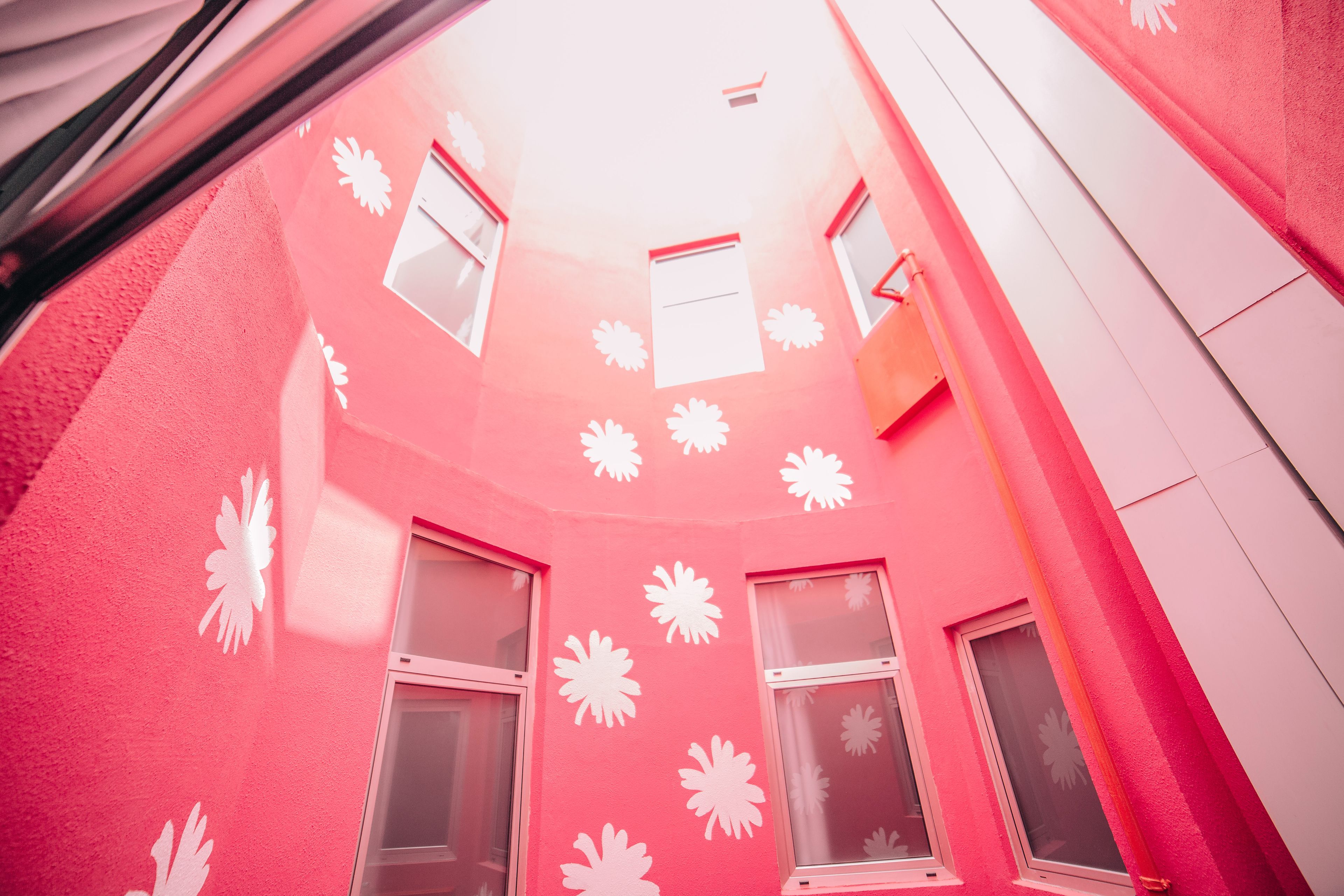 A pink building with white window frames and decorative patterns.