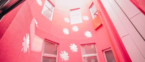 A pink building with white window frames and decorative patterns.