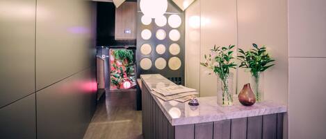 A modern reception desk with a marble top, two decorative vases, and a wall with circular light fixtures.