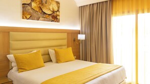 A hotel room with a large bed, a nightstand, a wall-mounted lamp, and a window with curtains. - The Ksar Djerba Charming Hotel & SPA (Djerba Midun)