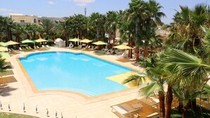 A large swimming pool surrounded by palm trees and sun loungers. - The Ksar Djerba Charming Hotel & SPA (Djerba Midun)