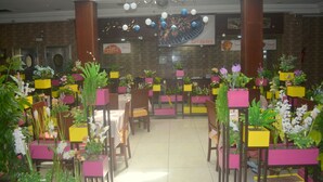 A restaurant with booths and tables, decorated with potted plants and flowers. - The Ksar Djerba Charming Hotel & SPA (Djerba Midun)