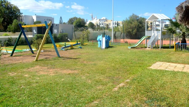 A playground with swings, slides, and a small shelter. - The Ksar Djerba Charming Hotel & SPA (Djerba Midun)