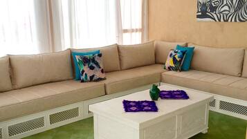 A living room with a beige sofa, a white coffee table, and green tiled flooring.