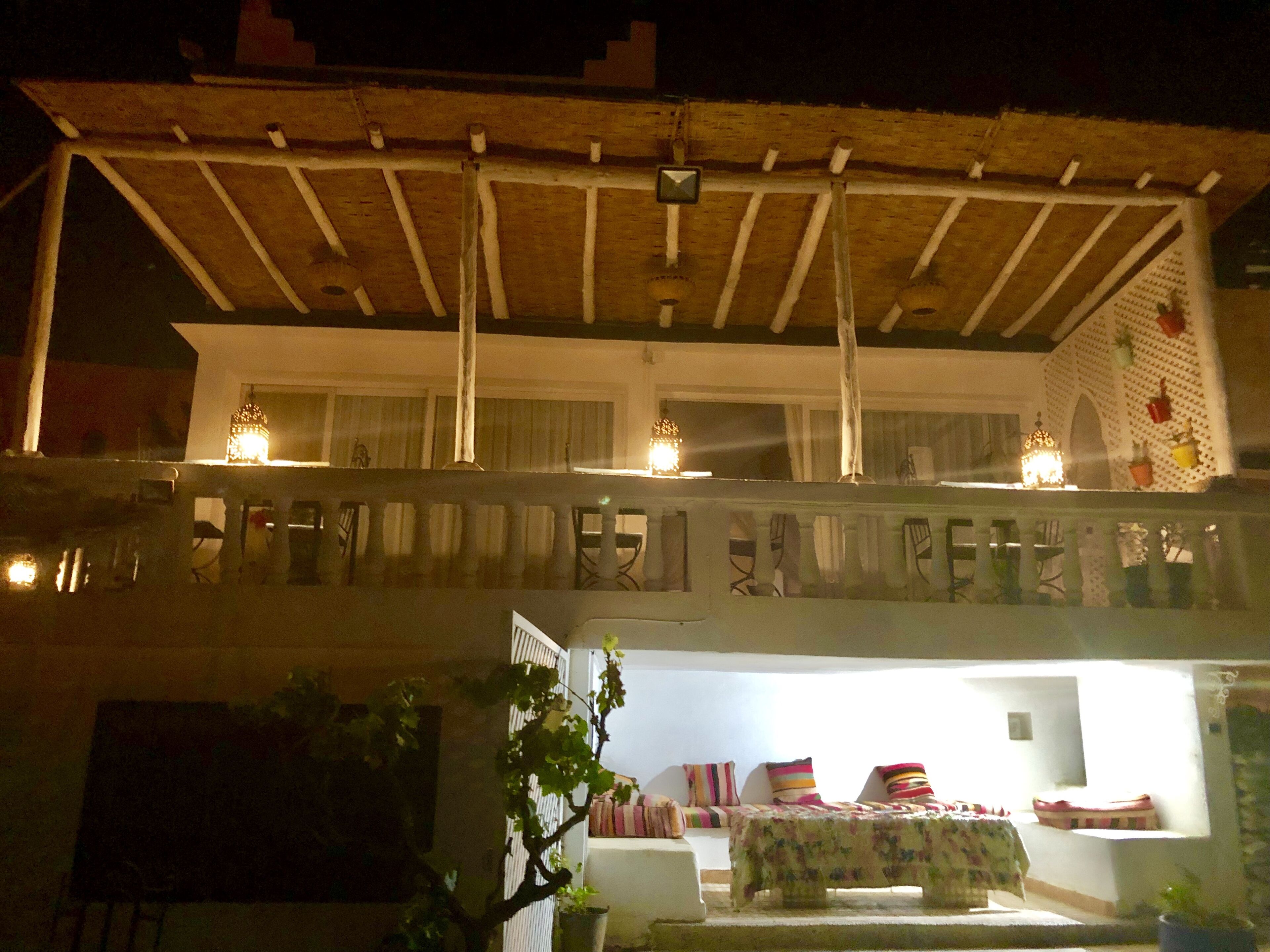 A two-story building with a balcony, a covered patio, and a small garden area.