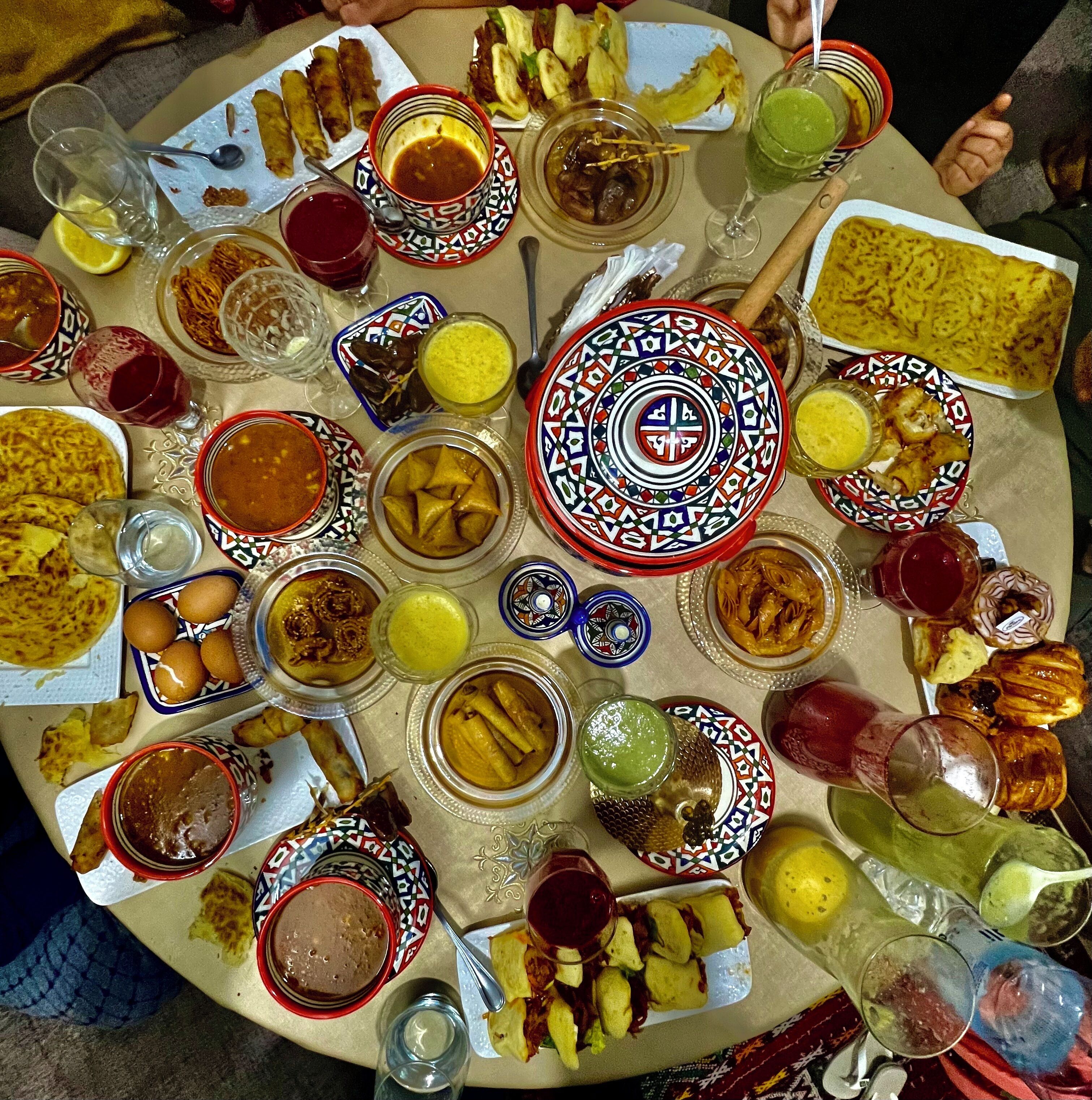 A round table with various dishes and drinks, including samosas, curries, and a samovar.