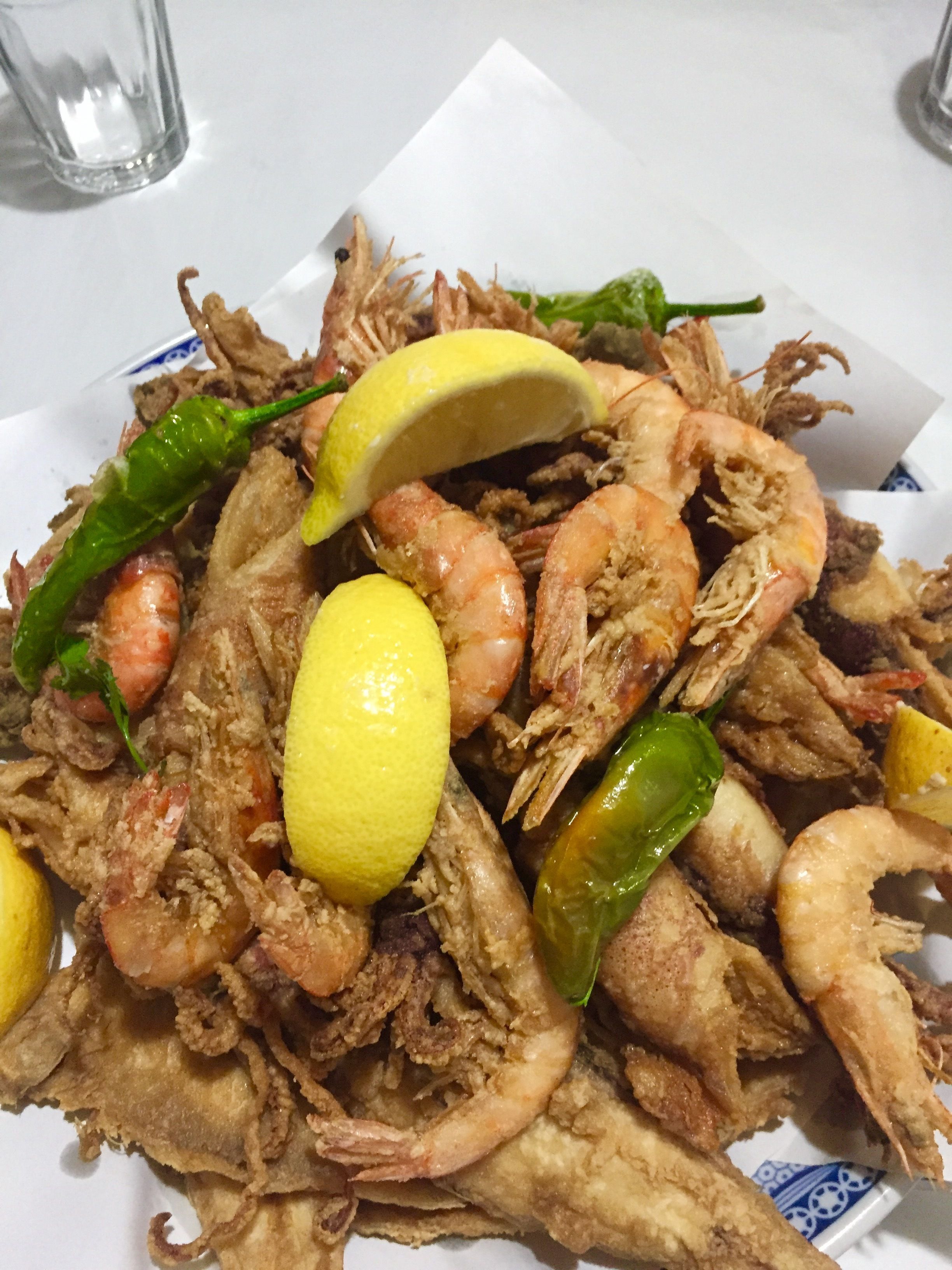 A plate of fried seafood with lemon slices and green chilies.