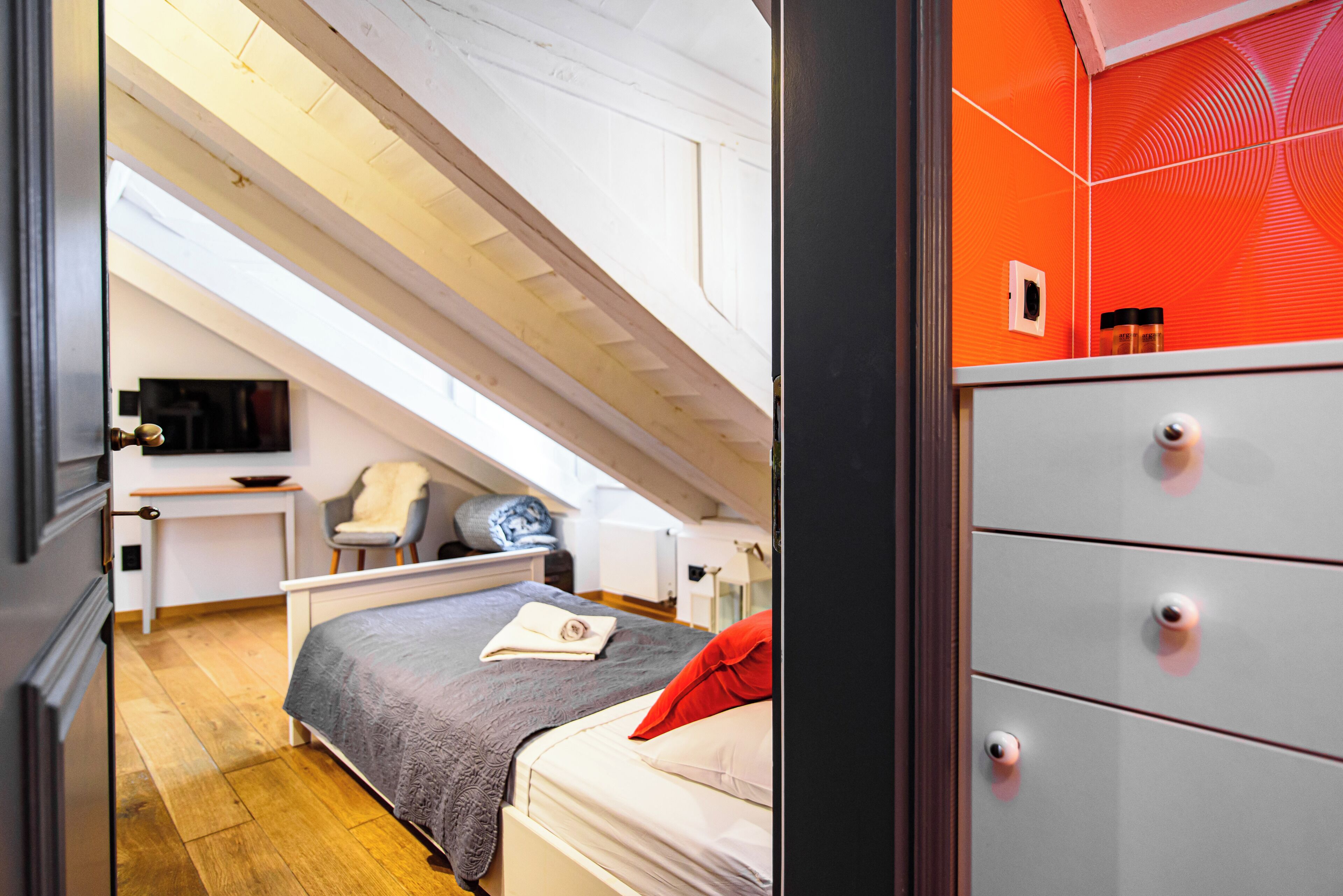 A bedroom with a bed, a desk, a chair, and a dresser.