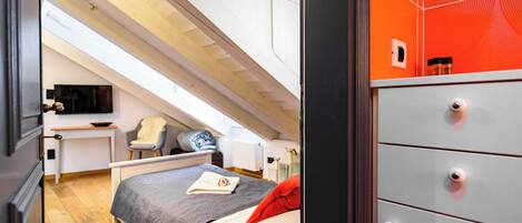 A bedroom with a bed, a desk, a chair, and a dresser.