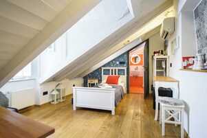 Una camera da letto con soffitto spiovente, un letto, una scrivania e una sedia.