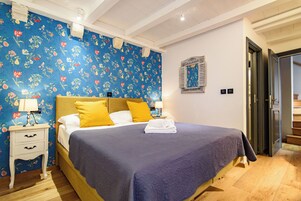 Quarto com cama, mesa de cabeceira e papel de parede floral.