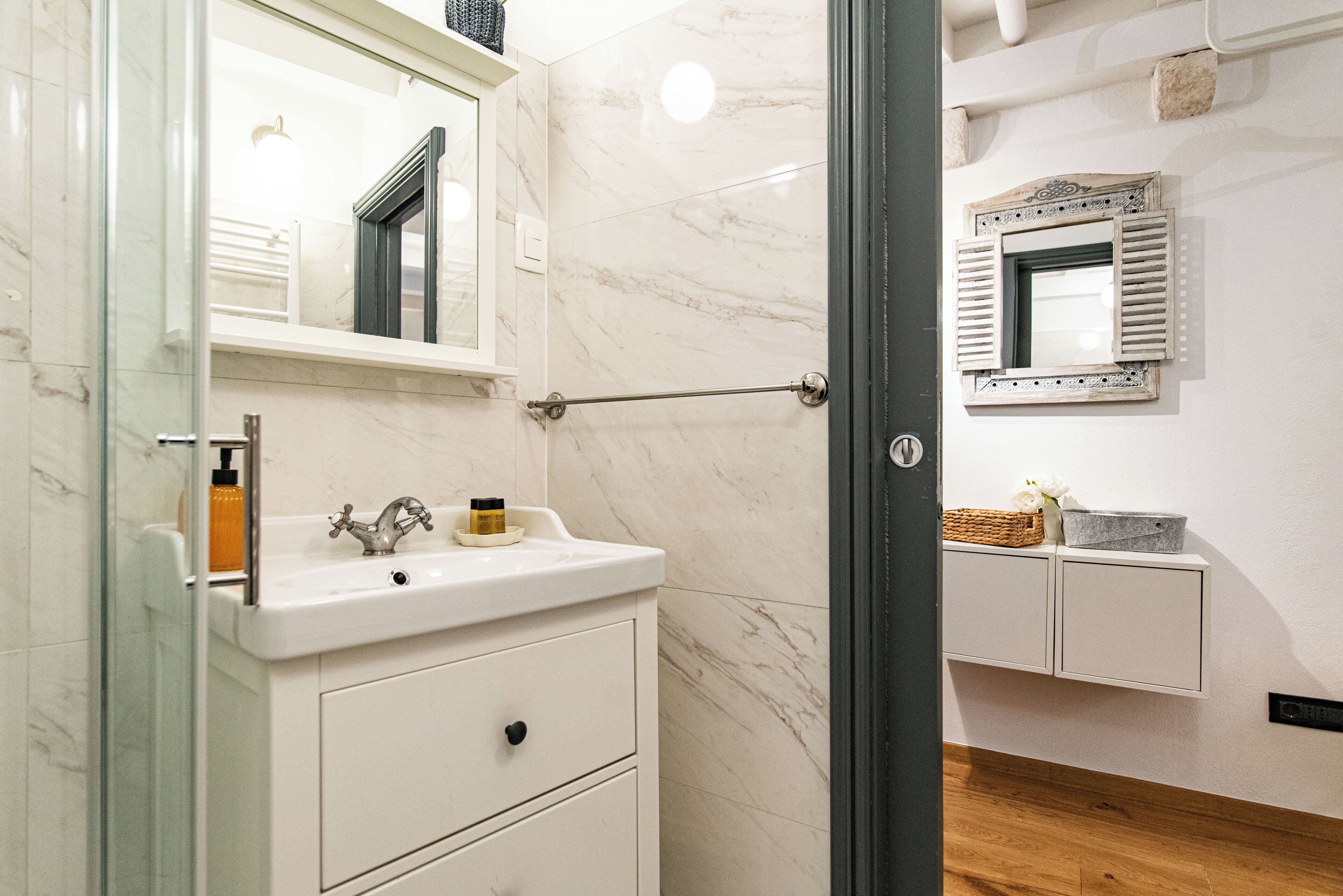 A bathroom with a marble sink, a mirror, and a wooden floor.