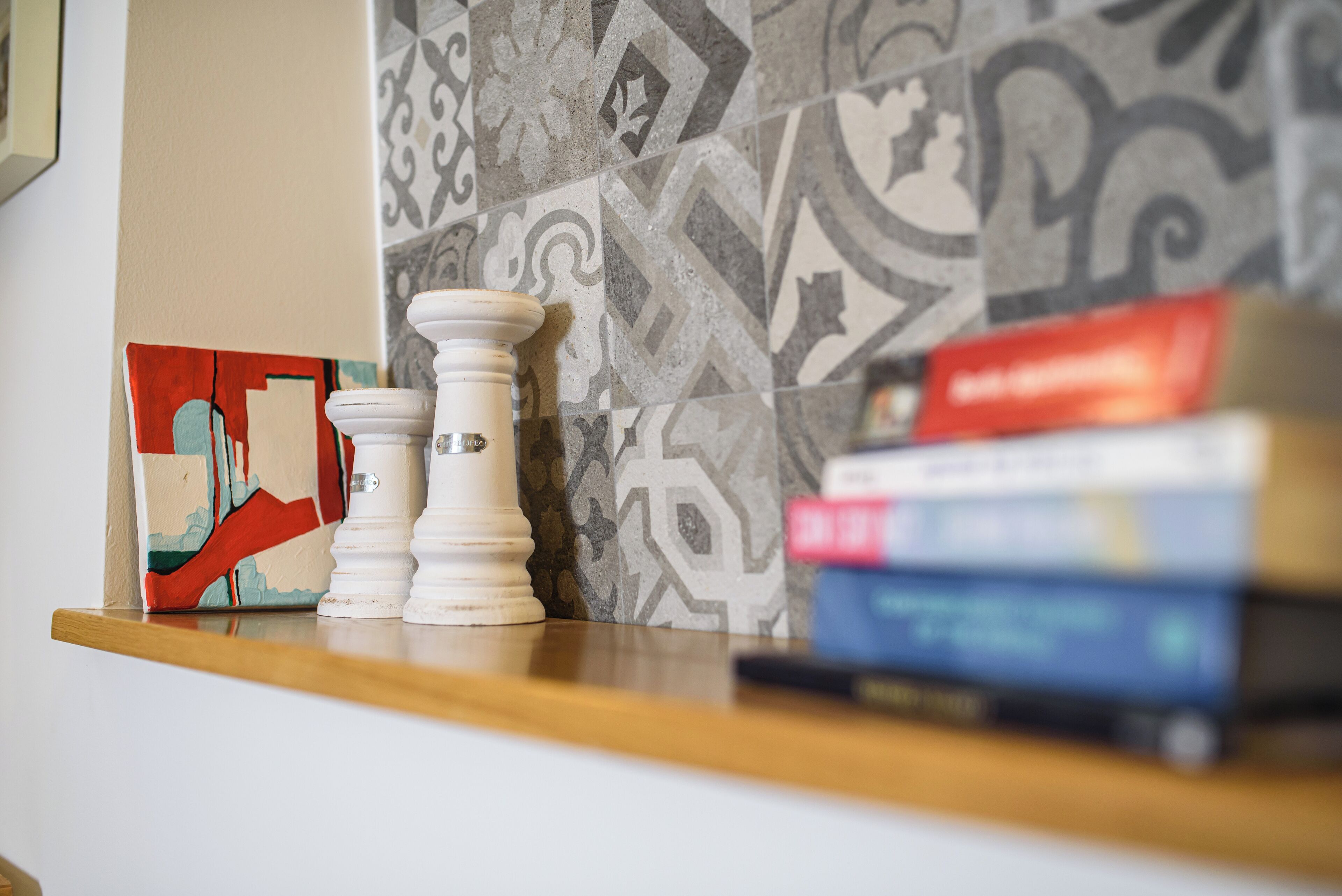A wooden shelf with a stack of books, a decorative object, and a framed artwork.