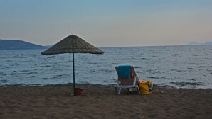 Escena de playa con una silla y una sombrilla.