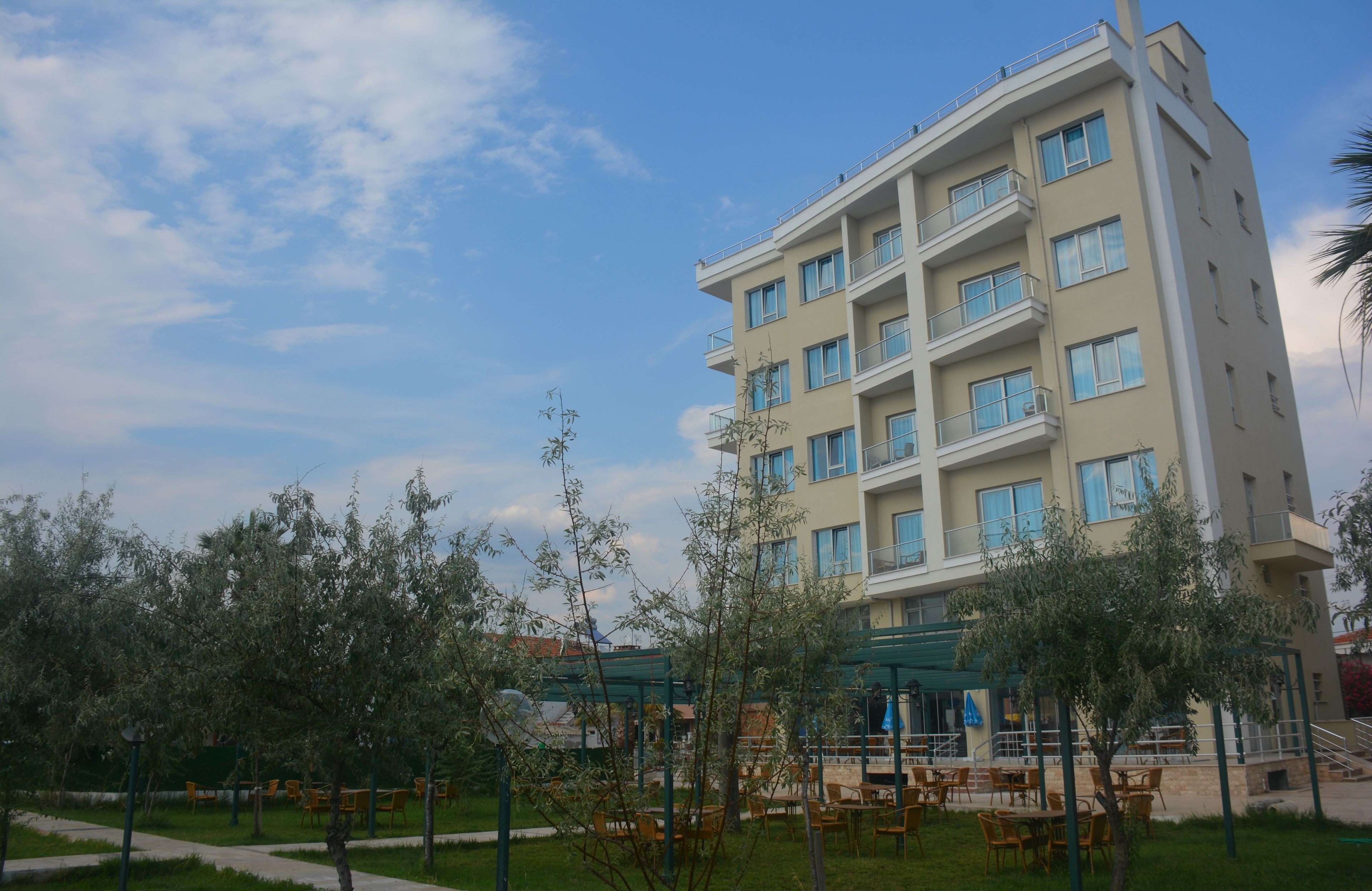 Un hotel a più piani con balconi, arredi esterni e una zona giardino.