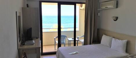 A hotel room with two beds, a desk with a computer, a chair, and a view of the ocean.