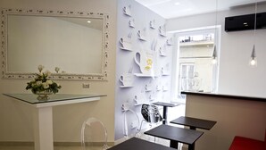A modern interior with a glass table, clear chairs, and a wall decorated with coffee cup designs.