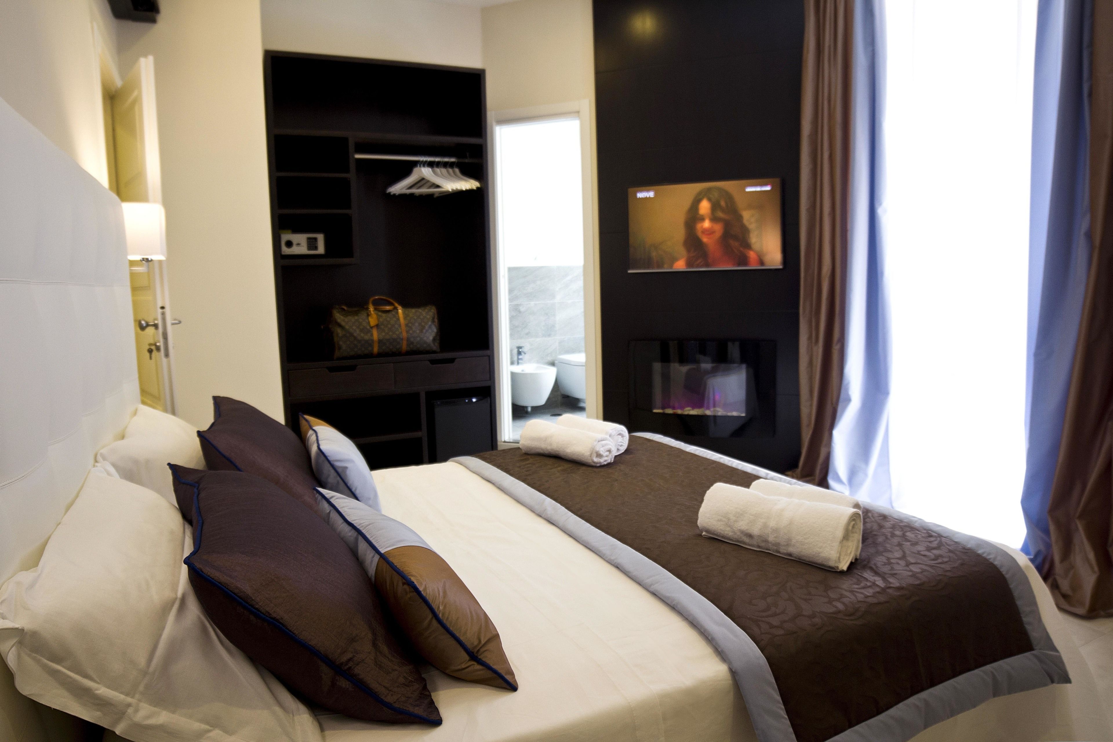 Une chambre d’hôtel avec un lit, une télévision, une armoire et une salle de bain visible à travers une porte ouverte.