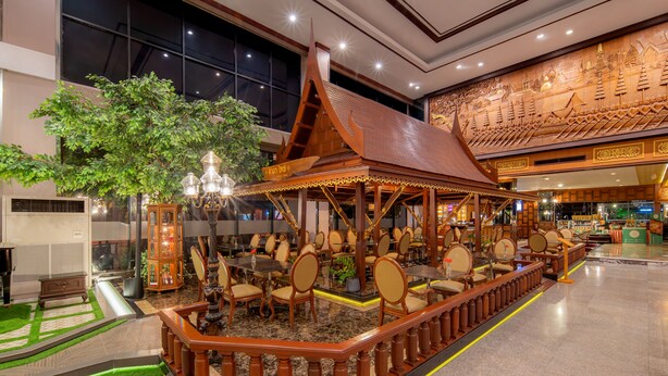 A traditional wooden pavilion with seating, surrounded by a decorative railing, in a well-lit indoor space. - Alexander Hotel (Bangkok)