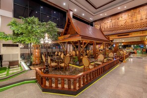 A traditional wooden pavilion with seating, surrounded by a decorative railing, in a well-lit indoor space. - Alexander Hotel (Bangkok)