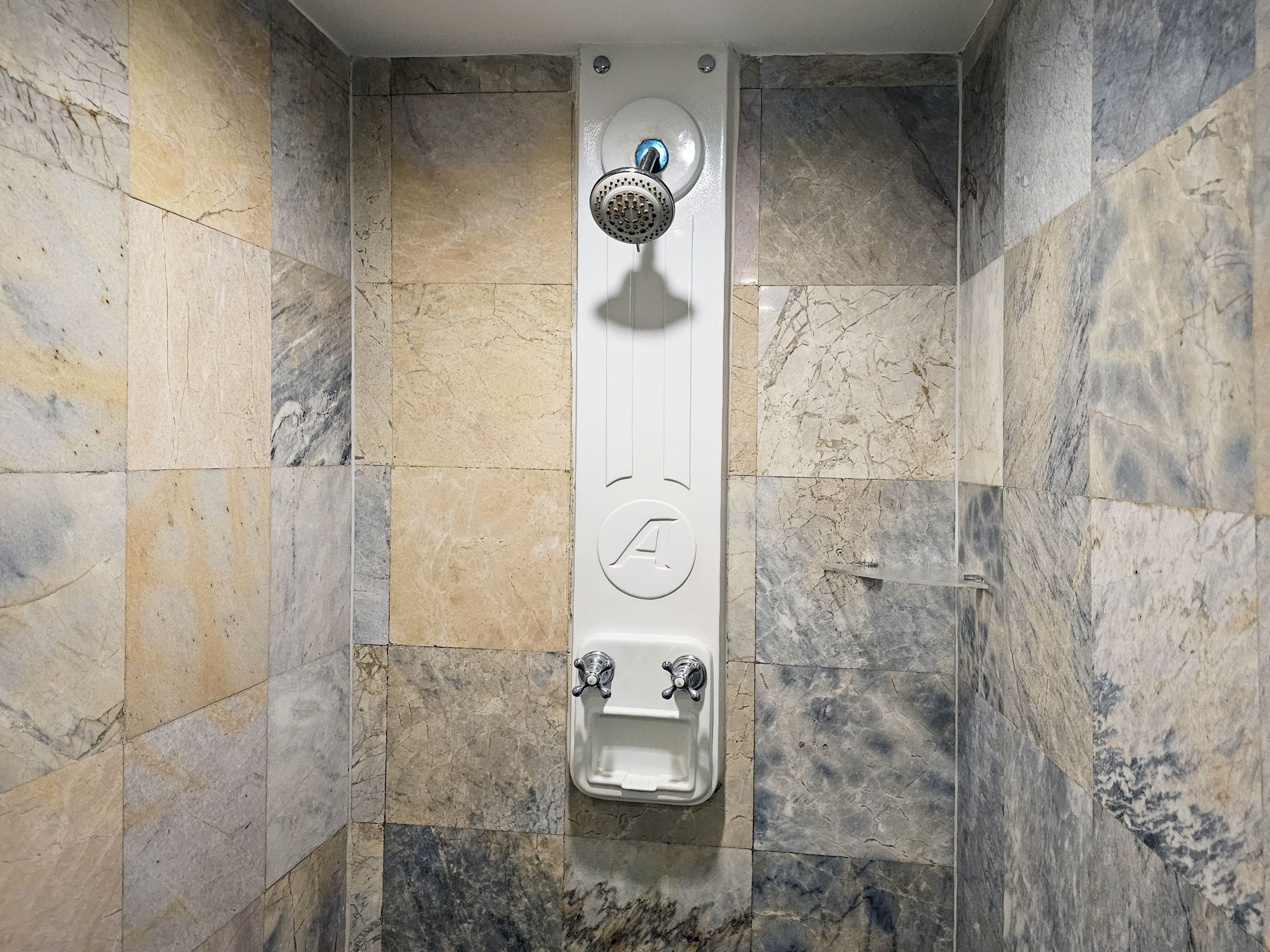 A shower with a wall-mounted control panel and a built-in seat.