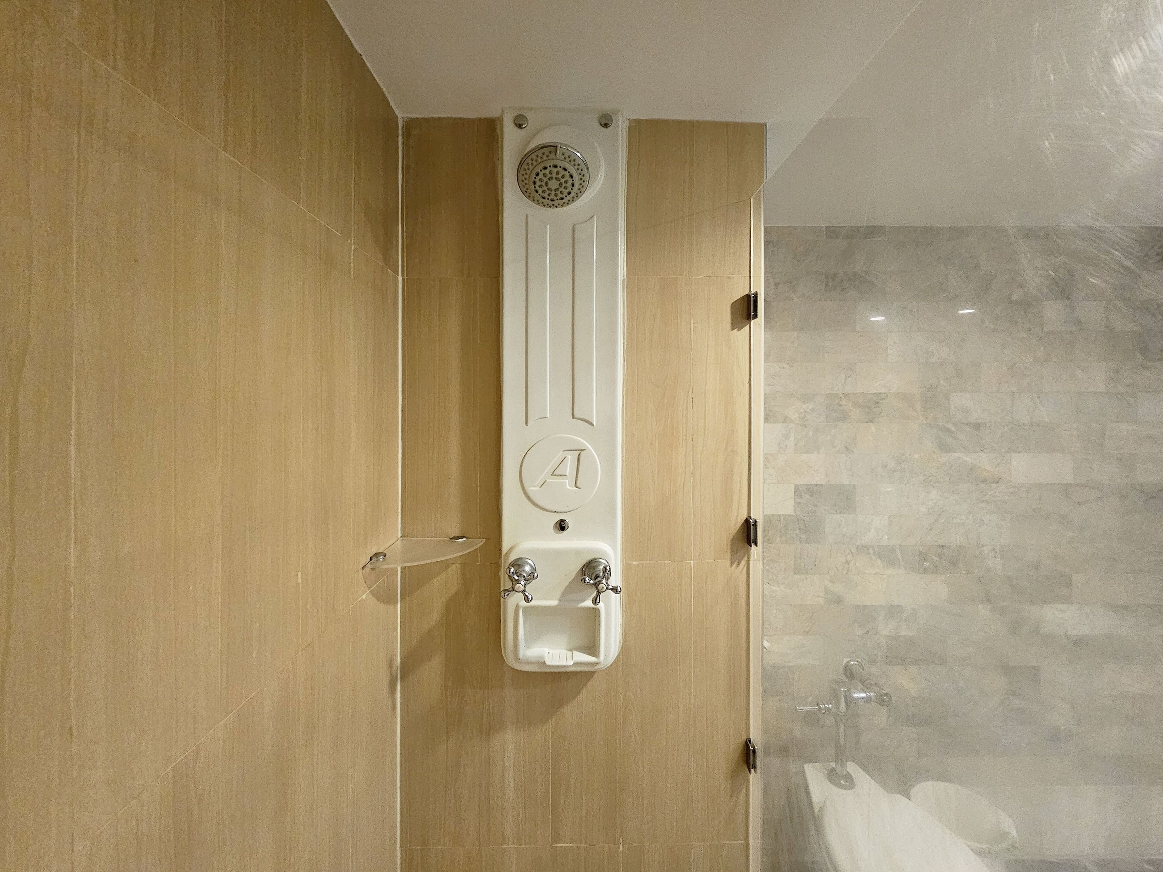 A modern bathroom with a vertical sink, a shower, and a toilet.