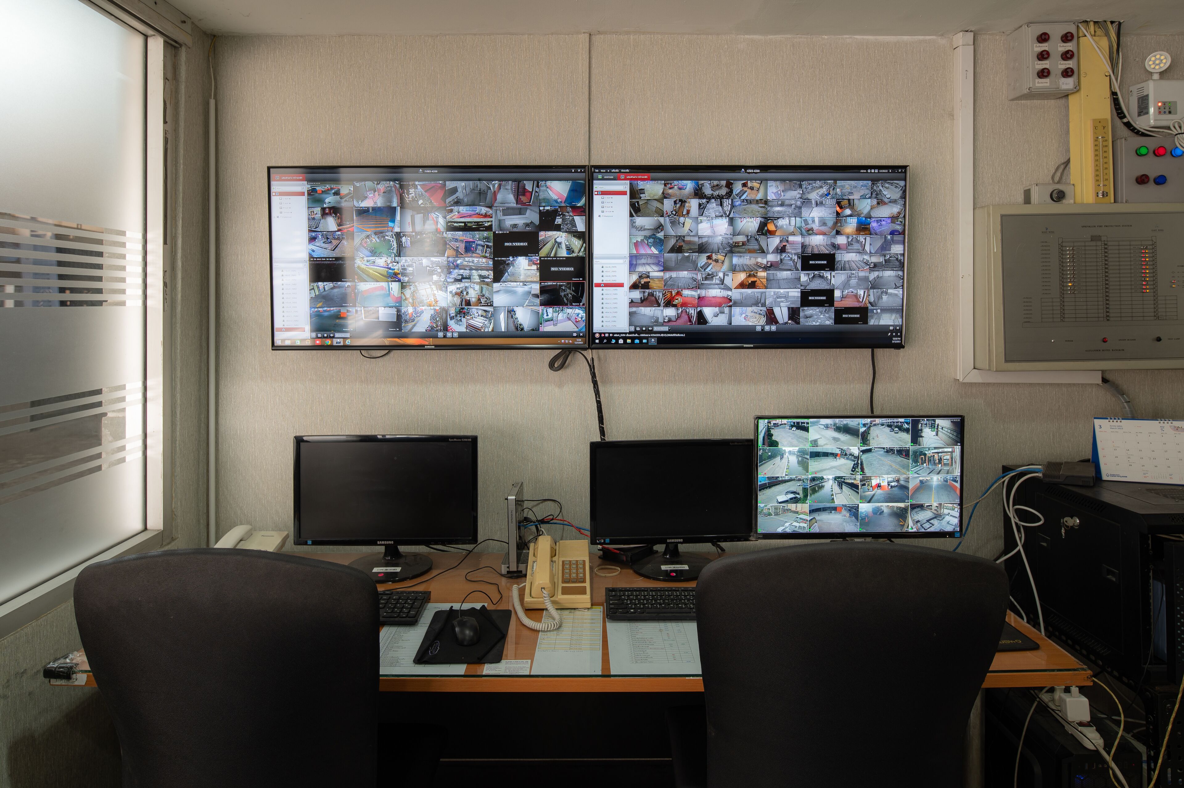 Une salle de contrôle équipée de plusieurs écrans affichant des images de vidéosurveillance, d’un téléphone et d’un bureau avec un ordinateur et un clavier.
