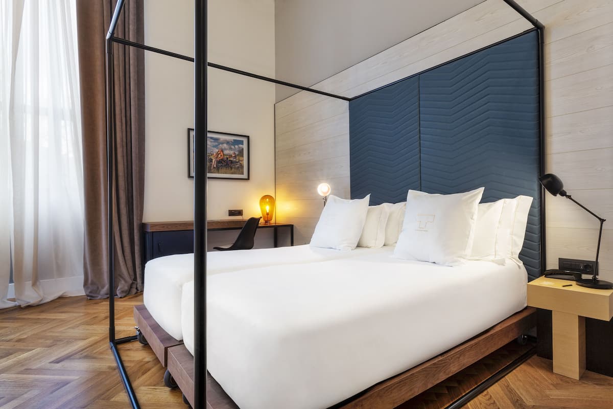 A modern hotel room with a large bed, a desk, and a chair.