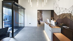 A modern office space with a reception desk, glass partitions, and contemporary lighting fixtures. - One Shot Tabakalera House (San Sebastián)