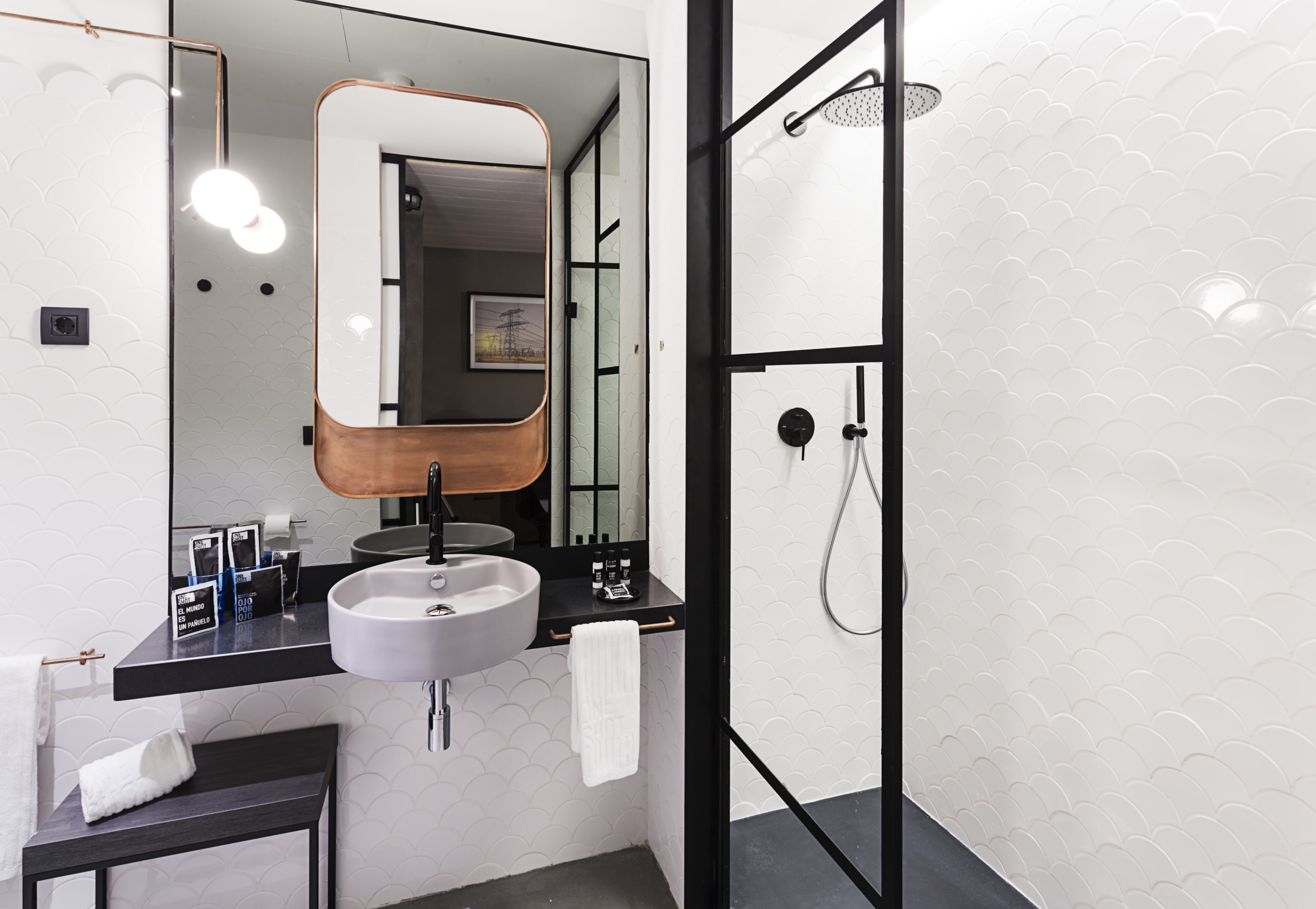 A modern bathroom with a large mirror, a sink, and a shower.