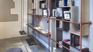A modern interior with a unique bookshelf design, a hanging chair, and a small round table. - One Shot Tabakalera House (San Sebastián)