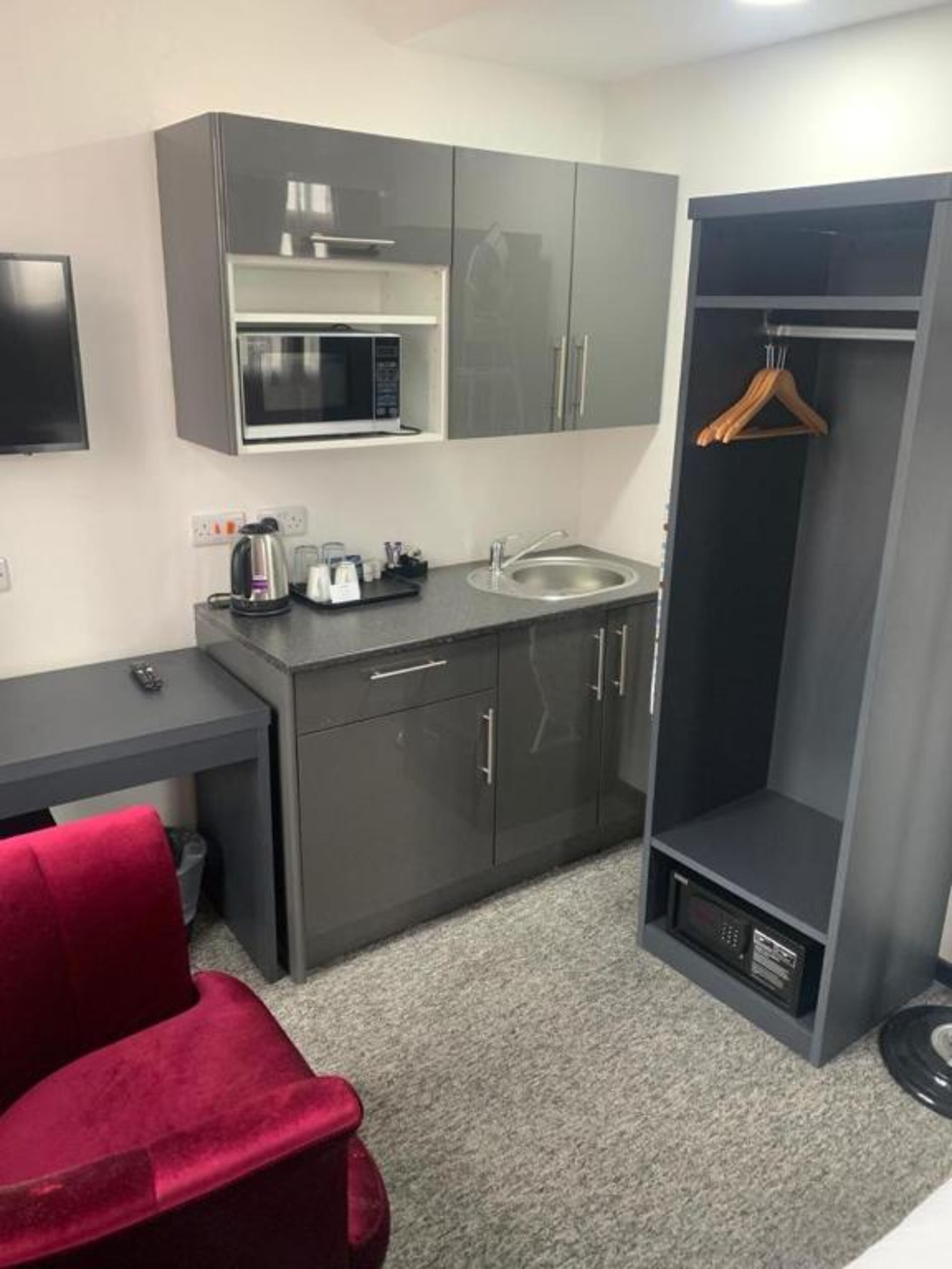 A compact kitchenette with a microwave, sink, and a small cabinet.