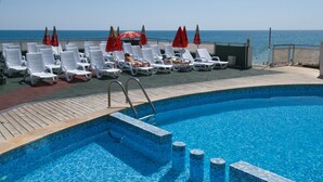 A poolside area with lounge chairs and umbrellas, a clear view of the sea, and a tiled pool. - Paraizo Beach - All Inclusive (Obzor)