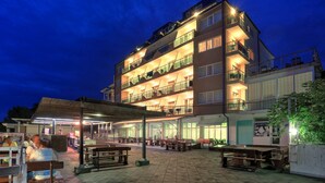 A multi-story hotel with outdoor seating areas and a covered patio. - Paraizo Beach - All Inclusive (Obzor)