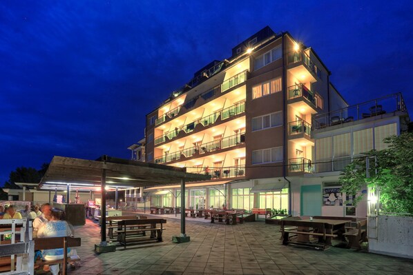A multi-story hotel with outdoor seating areas and a covered patio.